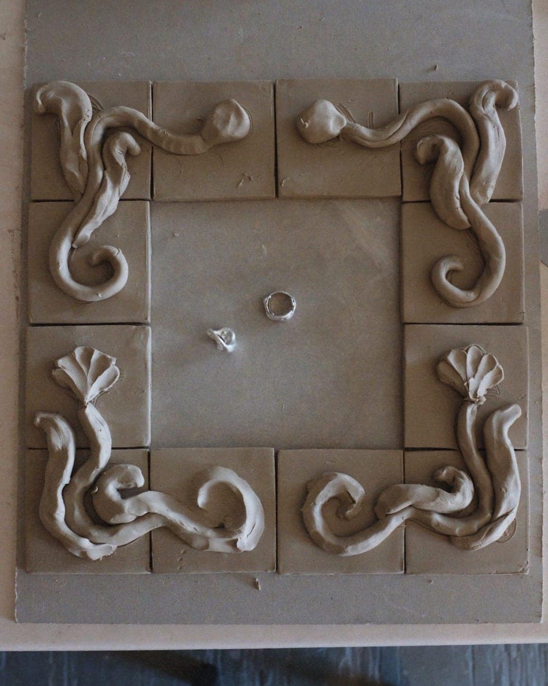 Relief tiles laid out as a square frame in wet clay
