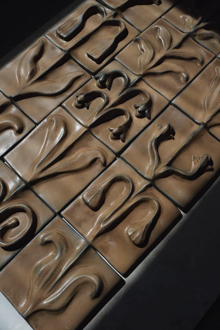 Mirror framed in relief tiles, leaning against a panelled wall